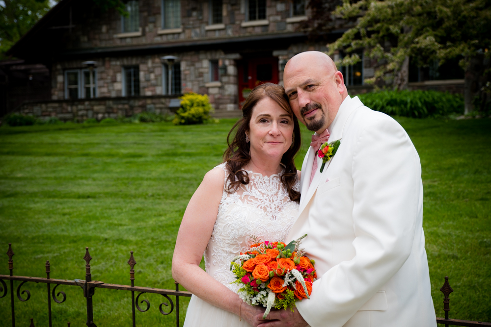 Bride and groom looking at the camera with the Stone Chalet Bed and Breakfast behind them